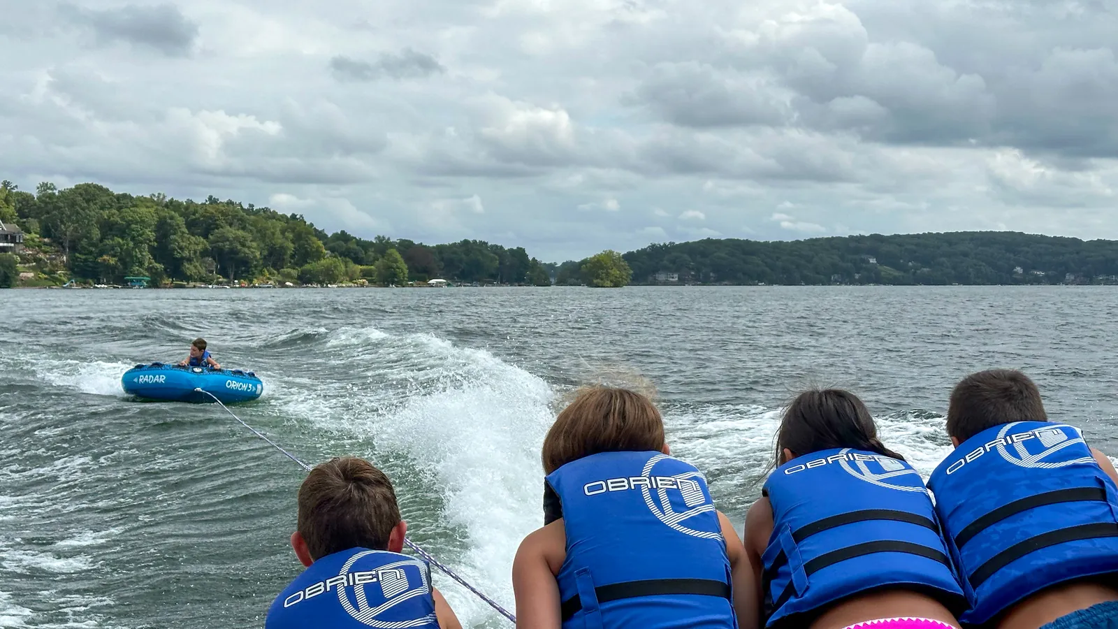 Three friends laughing as their tube bounces across Candlewood Lake