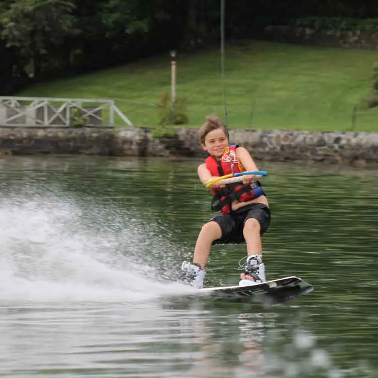 Young rider smiling while wakeboarding during a lesson on Candlewood Lake