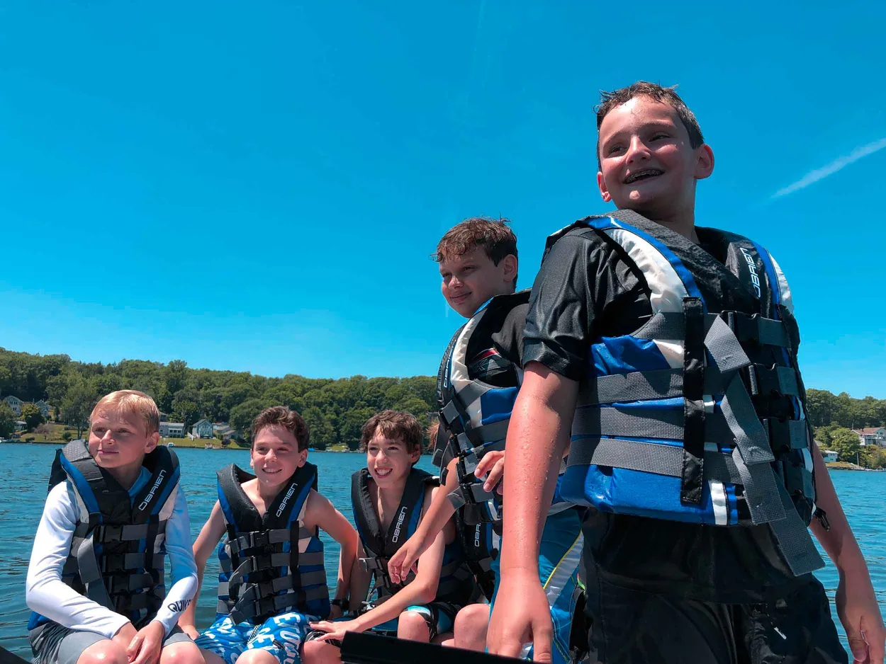 Kids in life jackets smiling aboard a Lakeside Watersports boat
