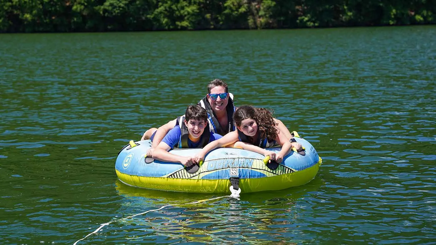 A family riding a tube together behind a Lakeside Watersports boat